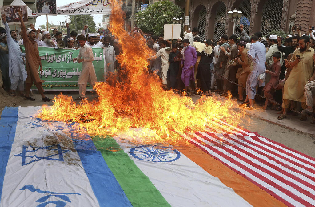 Pakistani protesters burn an Israeli flag 