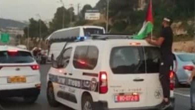 מפגינים בכביש 1 תולים דגל פלסטין על ניידת משטרה