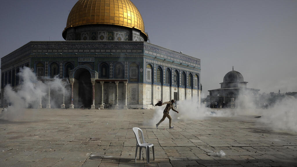 A Palestinian runs away from tear gas during clashes with Israeli security forces in front of the Dome of the Rock Mosque at the al-Aqsa Mosque compound on Monday 