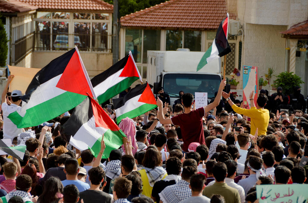 Jordanians hold flags as they demonstrate to express solidarity with the Palestinian people, near the Israeli embassy in Amman, Jordan 