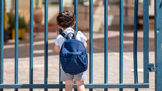 ילד ליד שער בית הספר
