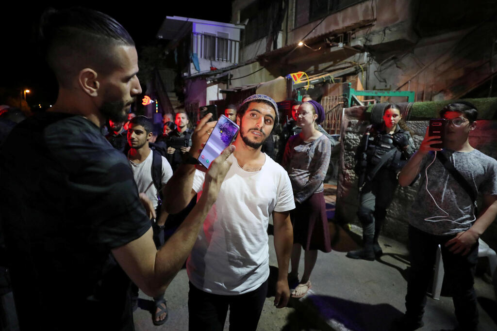 A Jewish resident and a Palestinian protester hold their mobiles to take pictures of each other amid ongoing tension in Sheikh Jarrah, May 5, 2021