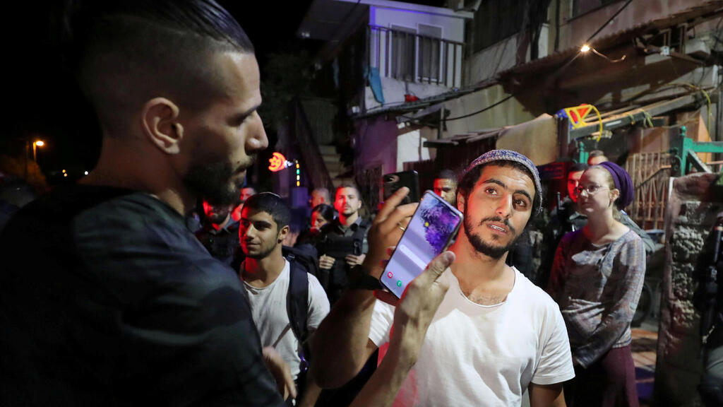 An Israeli Jewish resident and a Palestinian protester take photos of one another amid ongoing tensions in the East Jerusalem neighborhood of Sheikh Jarrah, May 2021 (Photo: Reuters) A Jewish resident and a Palestinian protester hold their mobiles to take pictures of each other amid ongoing tension in Sheikh Jarrah, May 5, 2021
