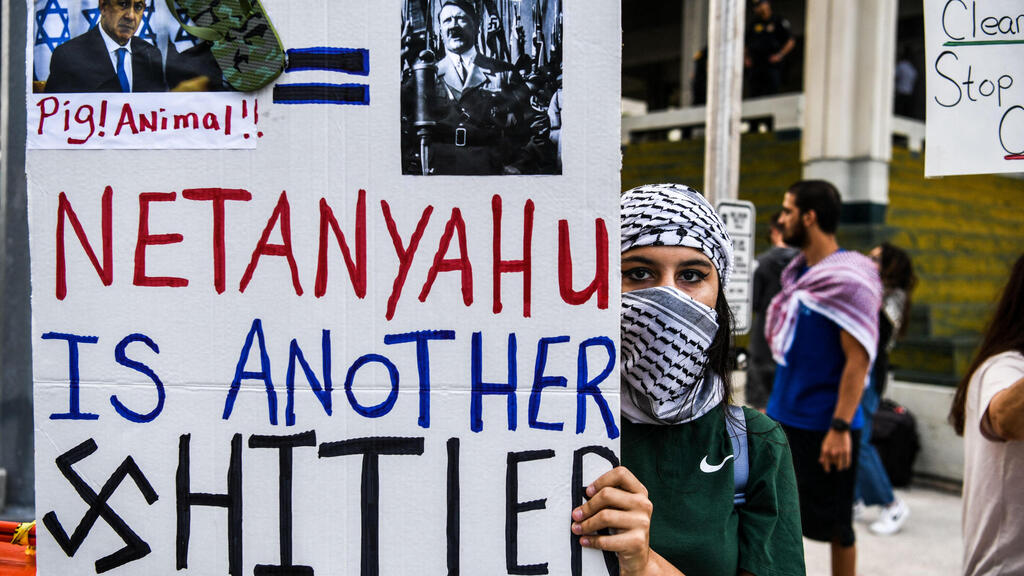   A woman in Florida holding a banner which calls Netanyahu 'Hitler' during a pro-Palestinian rally 
