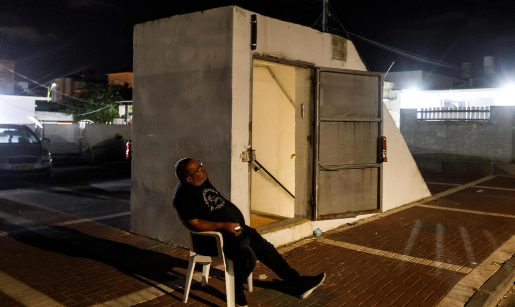 An Israeli man sits by the entrance to a bomb shelter as Israeli-Palestinian cross-border violence continues, in Ashkelon, southern Israel 
