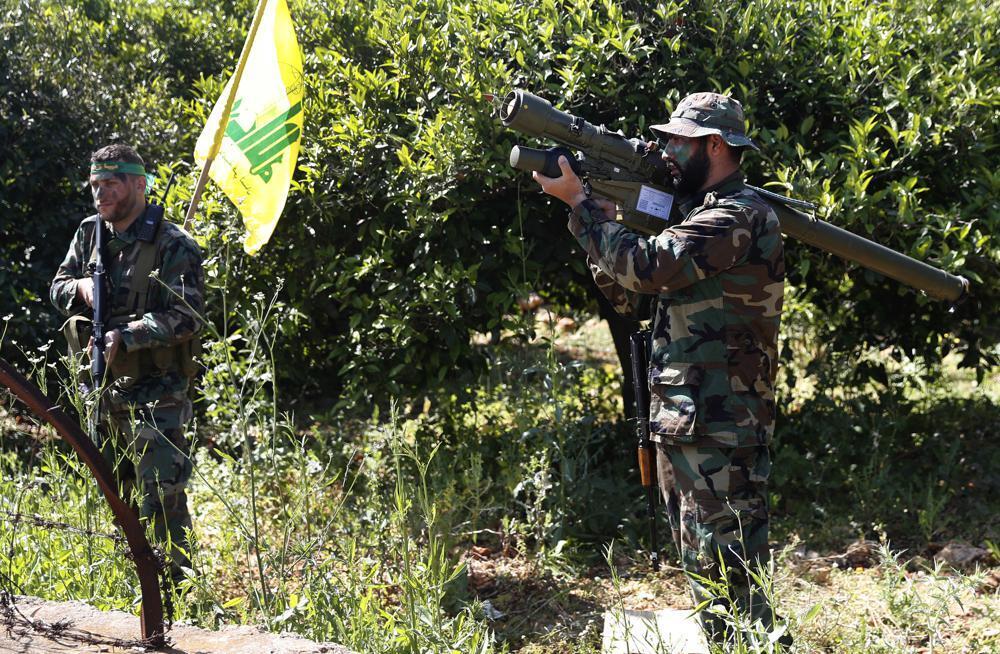 a Hezbollah fighter holds an Iranian-made anti-aircraft missile, right, as he takes his position with his comrade, left, between orange trees, at the coastal border town of Naqoura, south Lebanon 