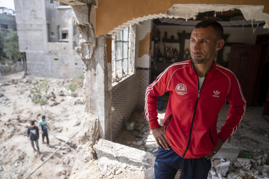 Nader al-Masri, a long-distance runner who participated in dozens of international competitions, including the 2008 Olympics, stands inside his severely damaged home