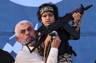 Hamas leader Yahya Sinwar holds the child of an Al-Qassam Brigades fighter, who was killed in the recent fighting with Israel 