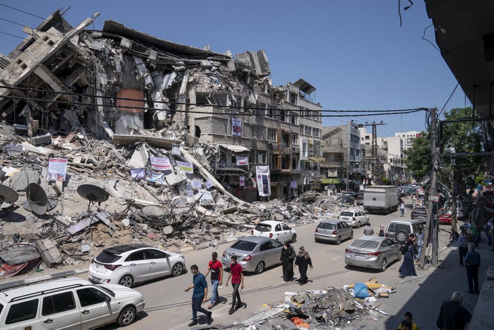 Motorists and pedestrians move past a building destroyed by an air-strike 