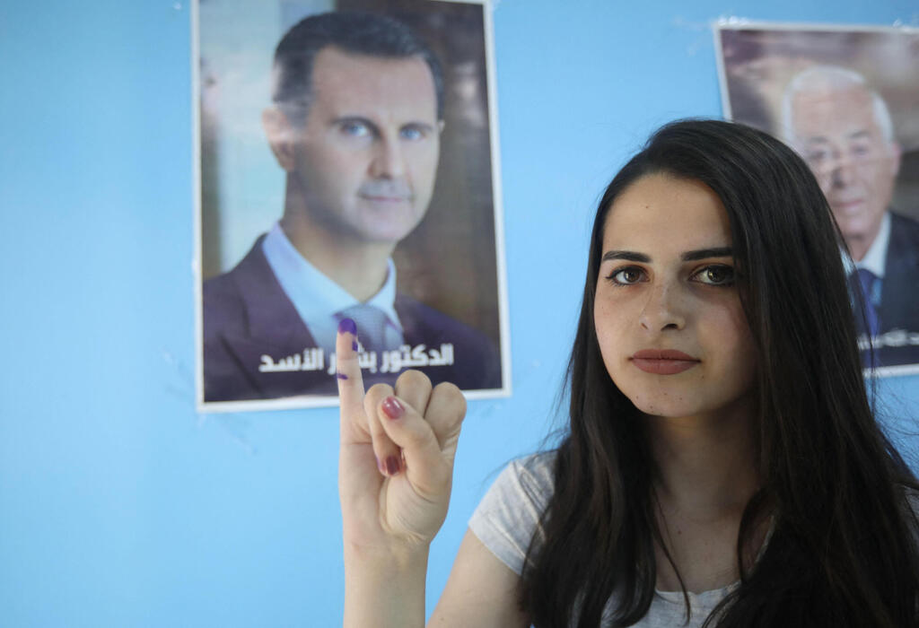 Syrian voter indicates at photo of Syrian President Assad at Damascus polling station on Wednesday 