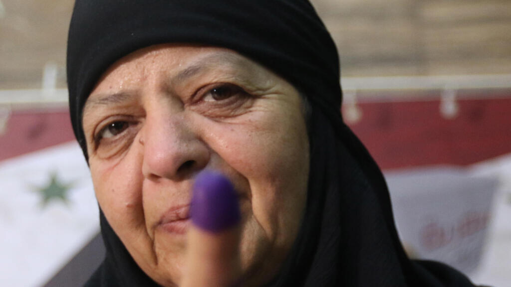 Syrian woman shows her finger marked with ink at after casting her vote in presidential election in Damascus on Wednesday 