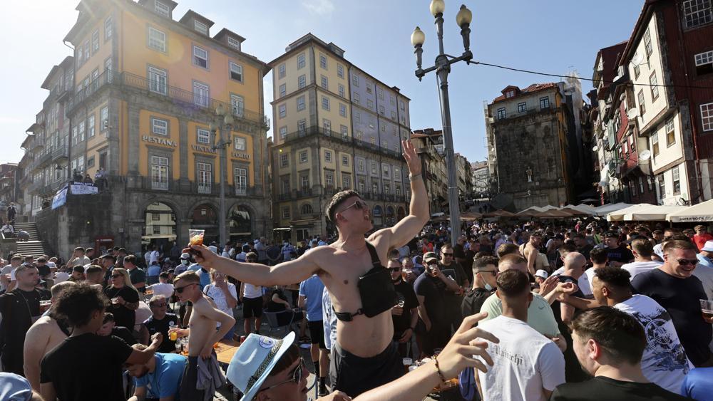 Manchester City supporters drink and chant by the Douro river bank in Porto, Portugal