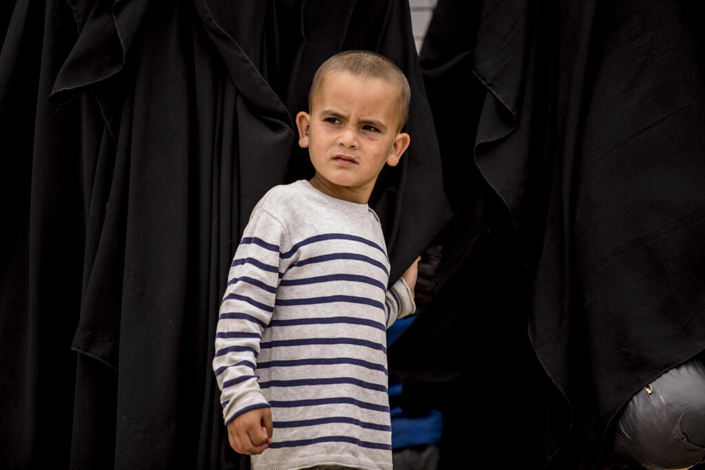A boy stands next to his mother at al-Hol camp, which houses families of members of the Islamic State group, in Hasakeh province, Syria, Saturday, May 1, 2021