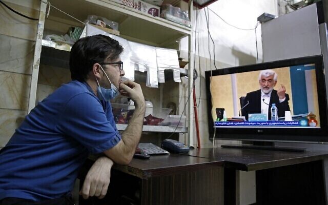 An Iranian vendor watches candidate Saeed Jalili speaking during the first televised debate between Iran presidential candidates, at a shop in Tehran 