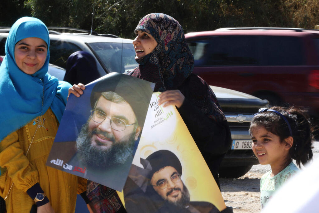 Shiite Lebanese women hold portraits of Hasan Nasrallah, the leader of Lebanon's Hezbollah movement near the border with Israel in the southern Lebanese village of Adaisseh, on May 25, 2021