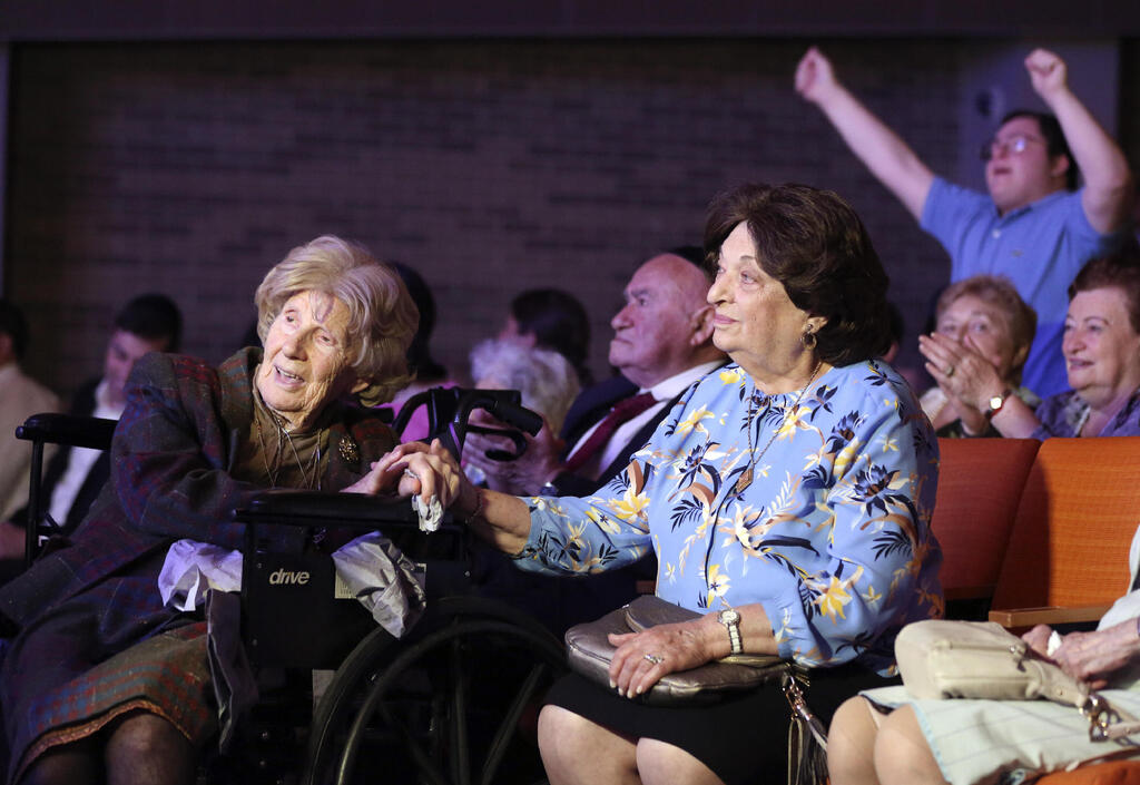 Aranka Engel, 103, left, holds the hand of fellow Holocaust survivor Jean Kurz, 81, at a concert honoring them in NY on Monday 