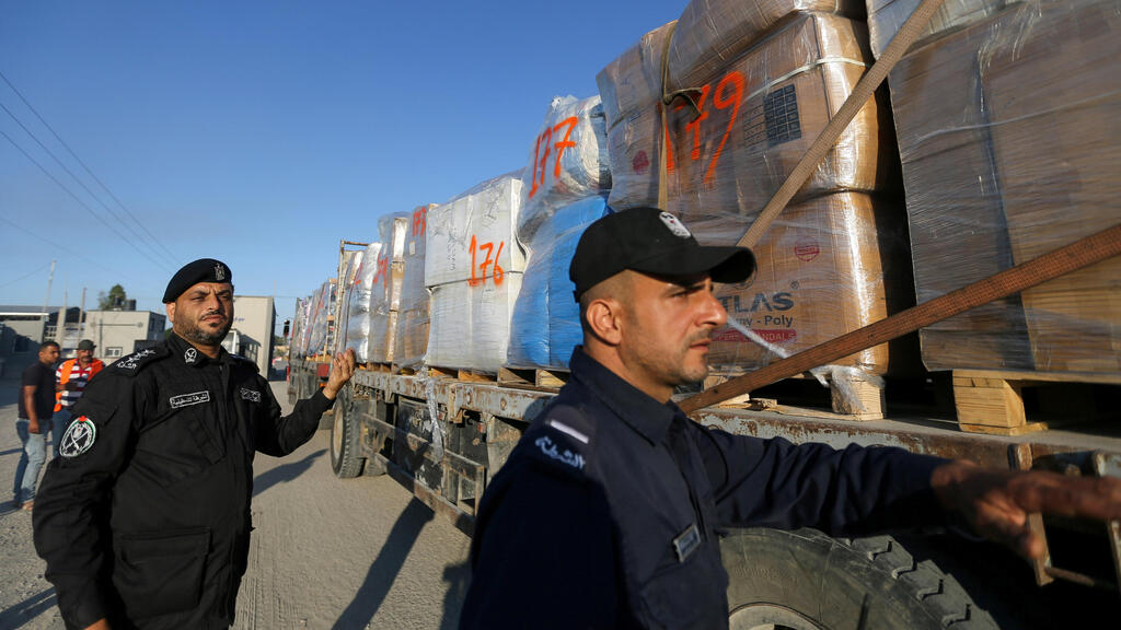 Palestinian police officers stand next to a truck carrying clothes for export at Kerem Shalom crossing in Rafah in the southern Gaza Strip,