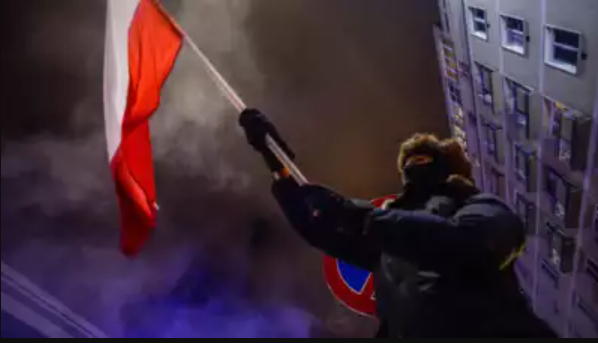 A person is waving the Polish flag during a protest