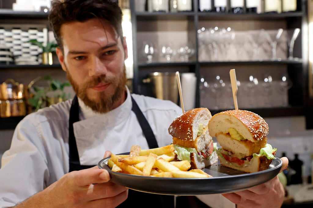Israeli Chef Shachar Yogev serves a burger made with "cultured chicken" meat at a restaurant adjacent to the SuperMeat production site in the central Israeli town of Ness Ziona 