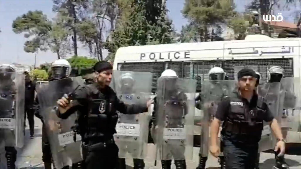 שוטרים פלסטינים מכים באלות מפגינים במחאה על ניזאר בנאת