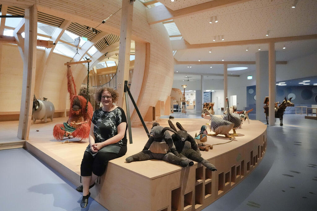 Ane Kleine-Engel, the head of the children's museum at the Jewish Museum pose for a photo as she is sitting between animals that are made out of recycled material, at the interactive exhibit about the story of Noah's Ark, in Berlin,