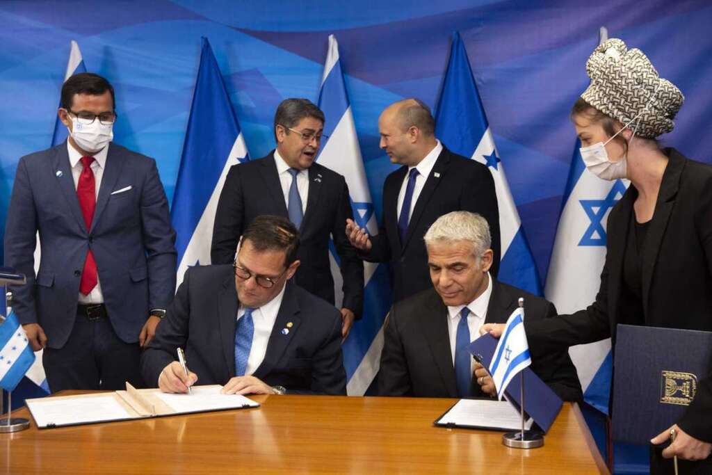 Prime Minister Naftali Bennett, back ceright, and Honduran President Juan Orlando Hernandez, speak as Israeli Foreign Minister Yair Lapid, front second right, and Honduran Foreign Minister Lisandro Rosales sign agreements between their two countries at the prime minister's office, in Jerusalem 
