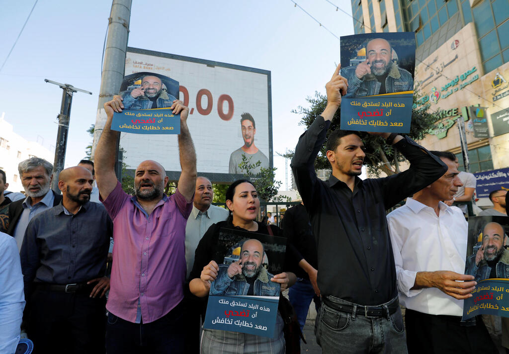 Demonstrators holding placards protest over the death of Nizar Banat, a critic of the Palestinian Authority, in Hebron, in the Israeli-occupied West Bank, June 27, 2021. Placards read, "This country deserves you to sacrifice, raise your voice and don't be afraid" 