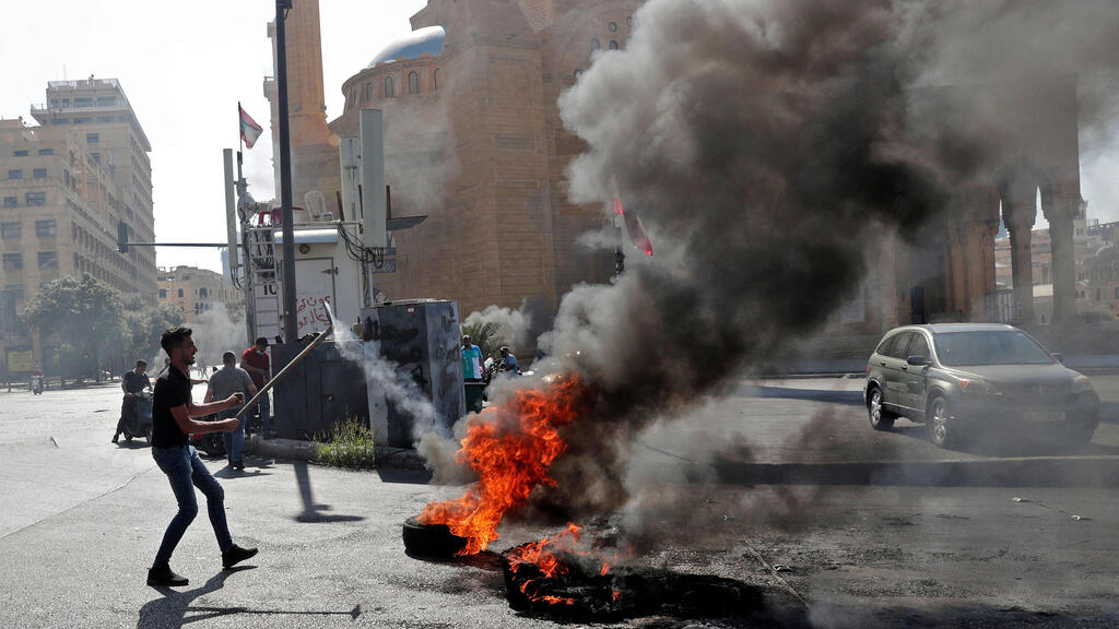 Lebanese forces watch anti-government protesters burn waste bins to block a highway that leads to the airport during a protest in Beirut, Lebanon, 26 June 2021