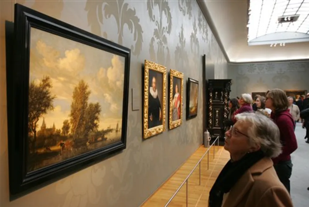 People look at a painting by Salomon van Ruysdael titled River Landscape with Ferry, left, at Rijksmuseum in Amsterdam, Netherlands, on February 4, 2006.