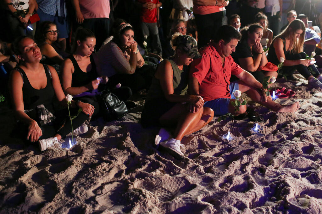 People attend a vigil in honor of residents of a partially collapsed residential building as the emergency crews continue search and rescue operations for survivors, in Surfside