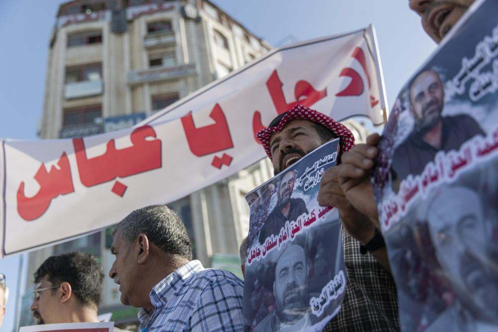 Demonstrators carry posters with pictures of Palestinian Authority outspoken critic Nizar Banat that reads "a Martyr of saying the truth in front of an ignorant Sultan," and a banner that reads "Abbas, leave," during a rally protesting his death, in the West Bank city of Ramallah 