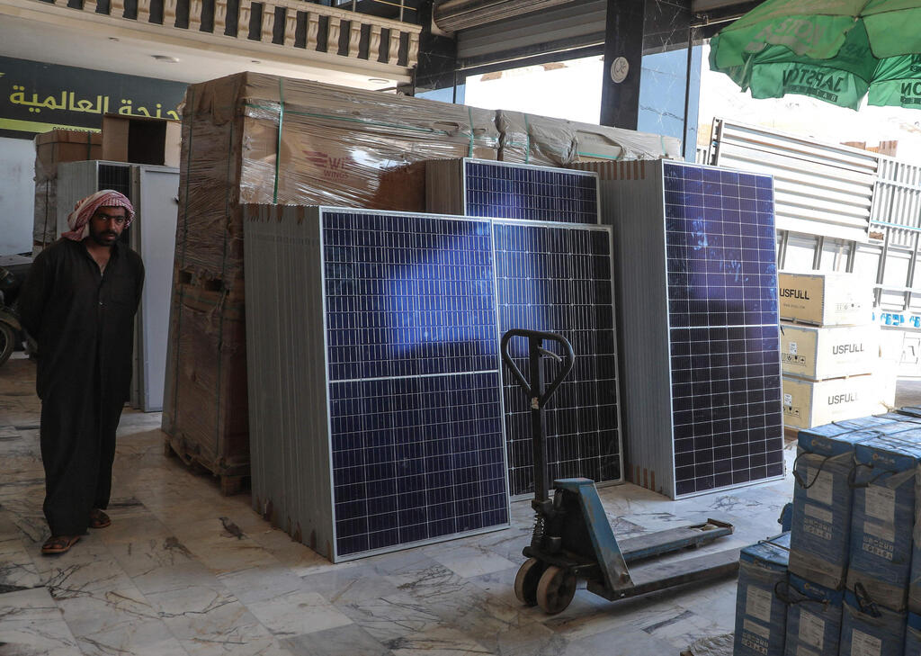 A man stands near solar panels displayed at a shop in the town of Dana, east of the Turkish-Syrian border in the northwestern Syrian Idlib province, on June 10, 2021