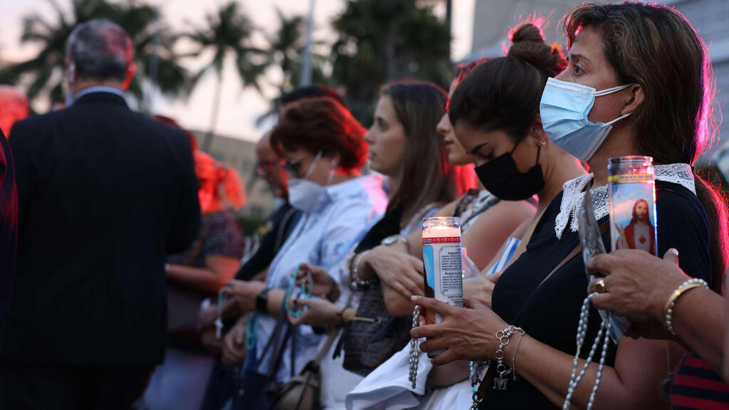 People gather at the memorial site for victims of the collapsed 12-story Champlain Towers South condo building to pray the rosary on July 07, 2021 in Surfside 
