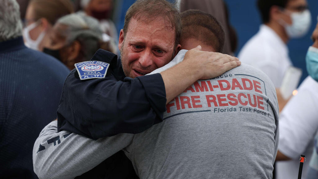 escue workers with the Miami Dade Fire Rescue embrace after a moment of silence near the memorial site for victims of the collapsed 12-story Champlain Towers South condo 