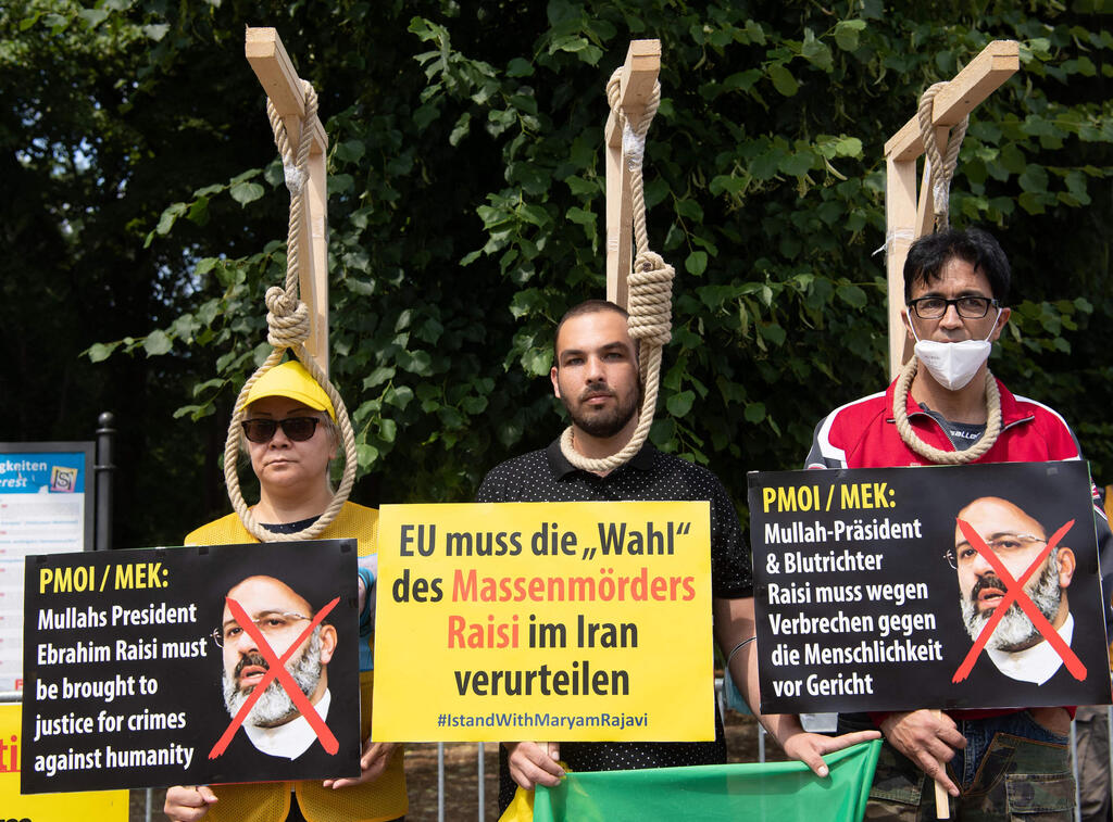 Demonstrators pose with mock-ups of gallows as they take part in a protest called by the National Council of Resistance of Iran (NCRI) against the Iranian regime in front of the Brandenburg Gate in Berlin on July 10, 2021