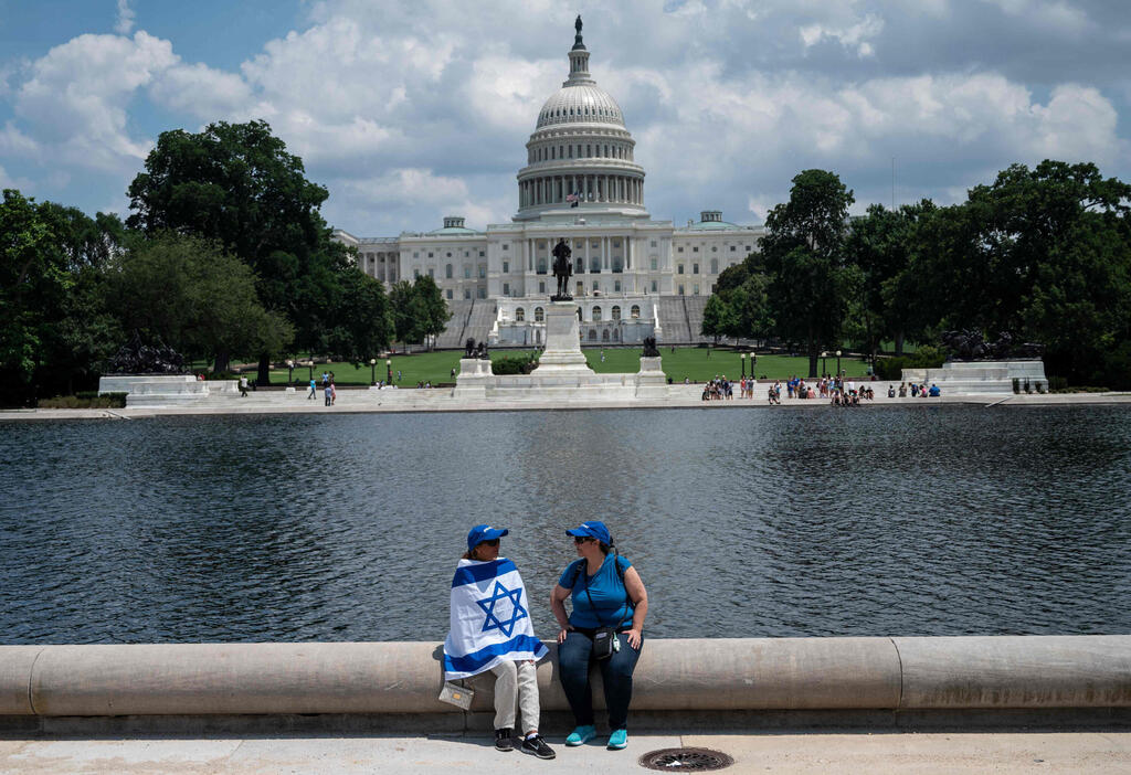  Two women take a break near the US Capitol during a rally on "No Fear: a Rally in Solidarity With the Jewish People" on the National Mall in Washington, DC on July 11, 2021
