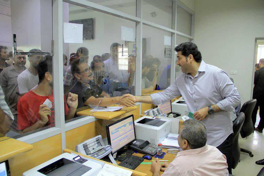 Official disburses Qatari aid money to Gaza civilians at a local postal bank