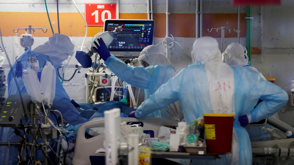Medical workers, seen through a window of an observation room, wear personal protective equipment (PPE) as they work inside an underground ward 