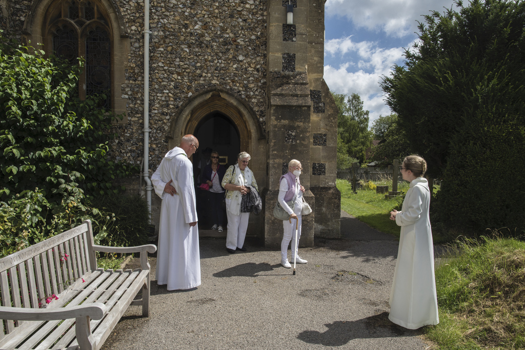The Rev. Jonathan Gordon, left, and Assistant Vicar Miranda Sheldon, right, greet Anglican worshippers at St. Mary's Church, Northchurch in Berkhamsted, England 