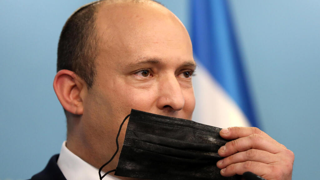 Prime Minister Naftali Bennett holds a face mask during a press conference regarding the COVID-19 situation in Israel 