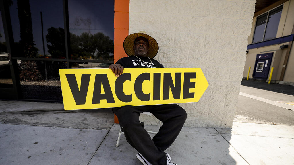 A man holding a sign indicating where vaccines were being administered in California last month (Photo: EPA) חיסון קורונה בארה"ב