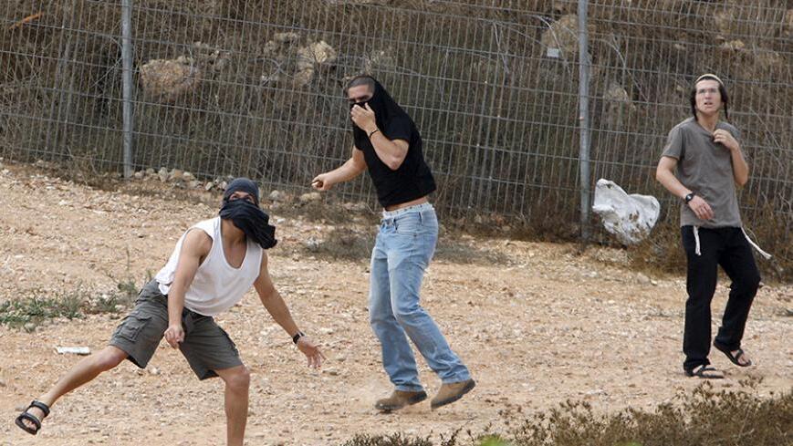 Israeli settlers throw stones at Palestinian houses (not seen) in the West Bank city of Hebron  