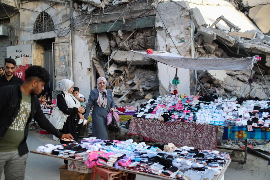 A Palestinian sells socks on a stall near the rubble of his old store that has been destroyed in an Israeli air strike, ahead of Eid Al-Adha Muslim holiday, in Gaza City 