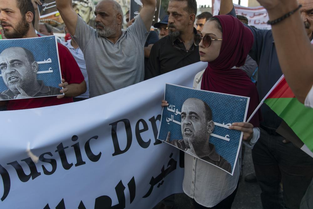 Demonstrators carry posters with pictures of Palestinian Authority outspoken critic Nizar Banat and reads "your voice is heard," during a rally protesting his death in the West Bank city of Ramallah 