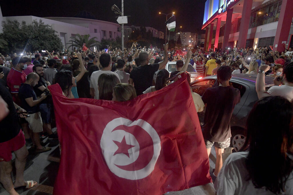 People celebrate in the street after Tunisian President Kais Saied announced the dissolution of parliament and Prime Minister Hichem Mechichi's government in Tunis 
