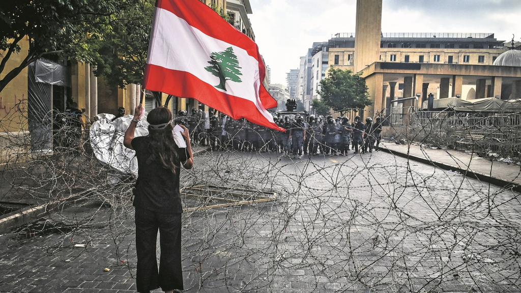 A protestor holding a Lebanese flag demonstrates over Lebanon's economic meltdown and political crisis in Tripoli 