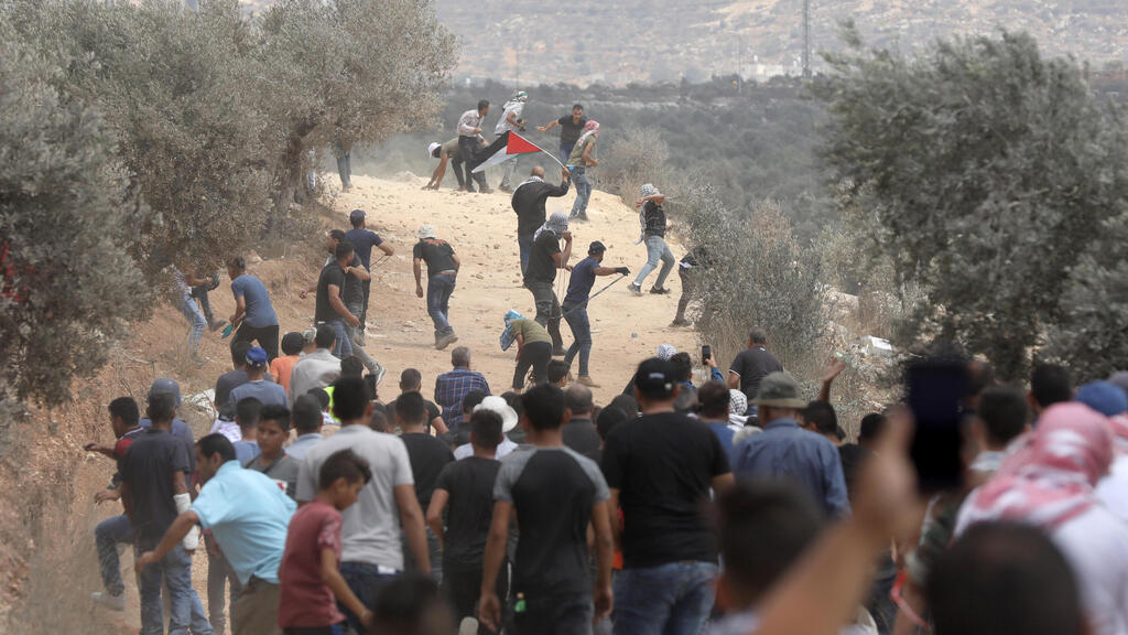 Palestinian protesters throw stones at Israeli troops during clashes after a demonstration against the expansion of the new Jewish outpost of Eviatar on the lands of Beita village  