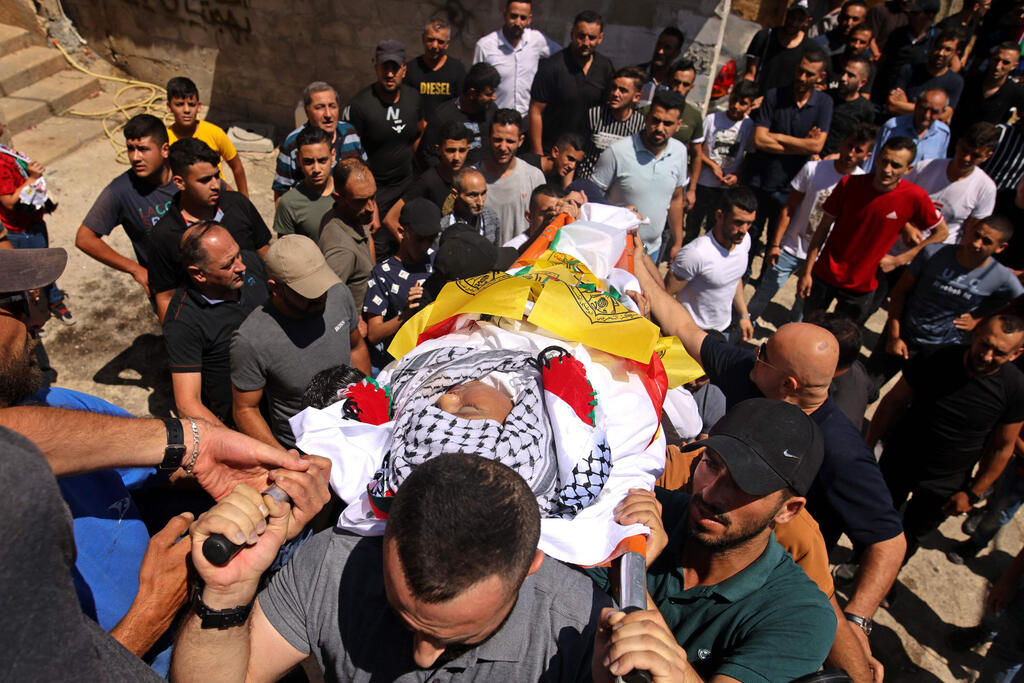 Mourners carry the body of Palestinian boy Mohamad al-alami during his funeral in the town of Beit Omar 