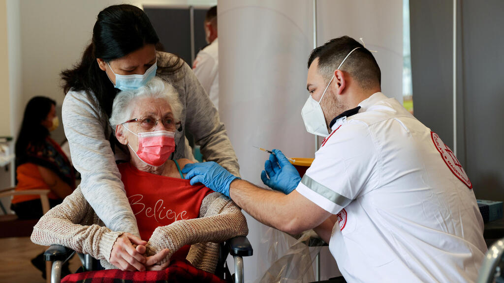 An elderly woman receives a booster shot of her vaccination against the coronavirus disease (COVID-19) at an assisted living facility, in Netanya, Israel January 19, 2021 
