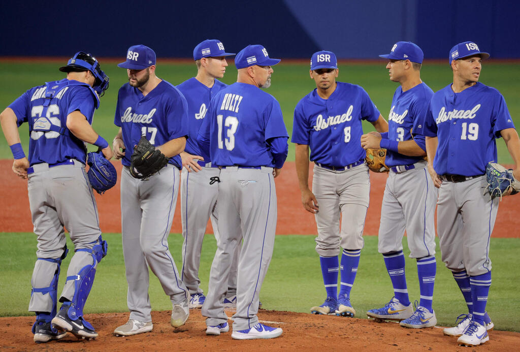 Israel's head coach Peter Kurz (C) talks to his players during the fourth inning of the Tokyo 2020 Olympics 